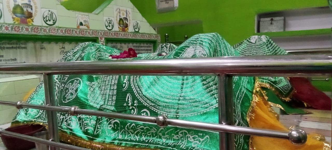 The sacred mazar (tomb) of Huzoor Maharaj — covered with the traditional green chadar with Quranic calligraphy and rose petals